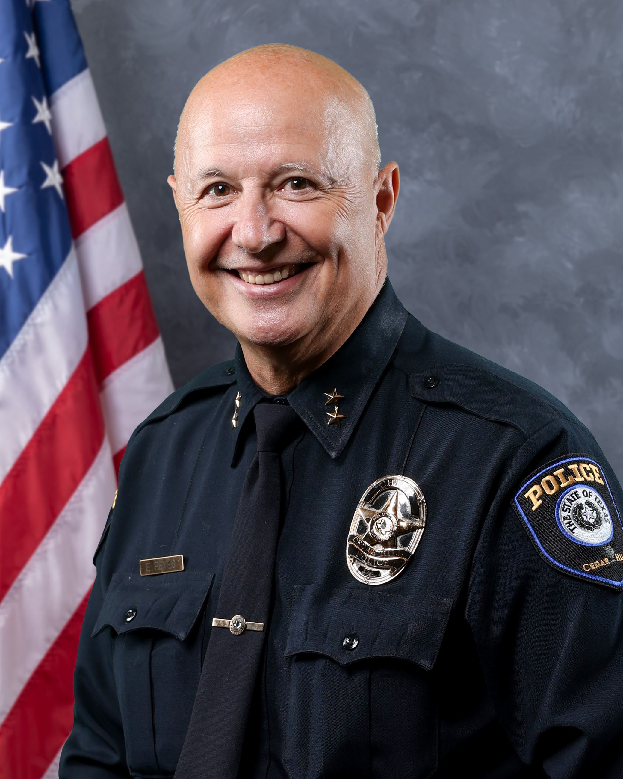 Man in police uniform in front of blue background with American flag